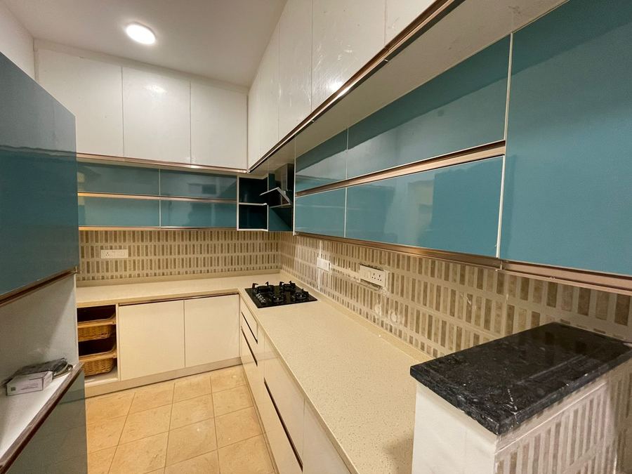 Modular kitchen with teal glass-shutter cabinets and stone countertop