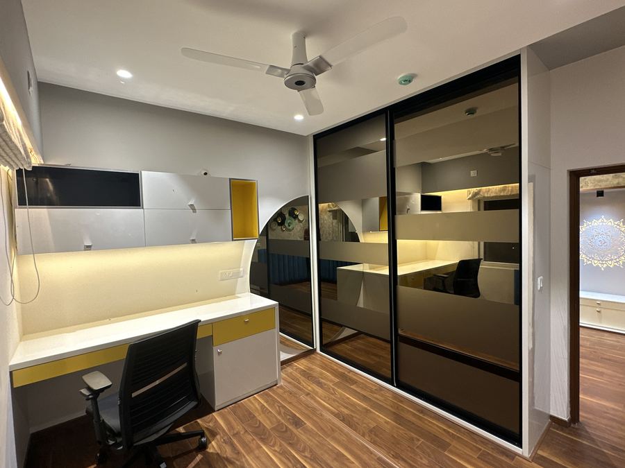 Study nook with yellow-accent desk beside a mirrored sliding wardrobe